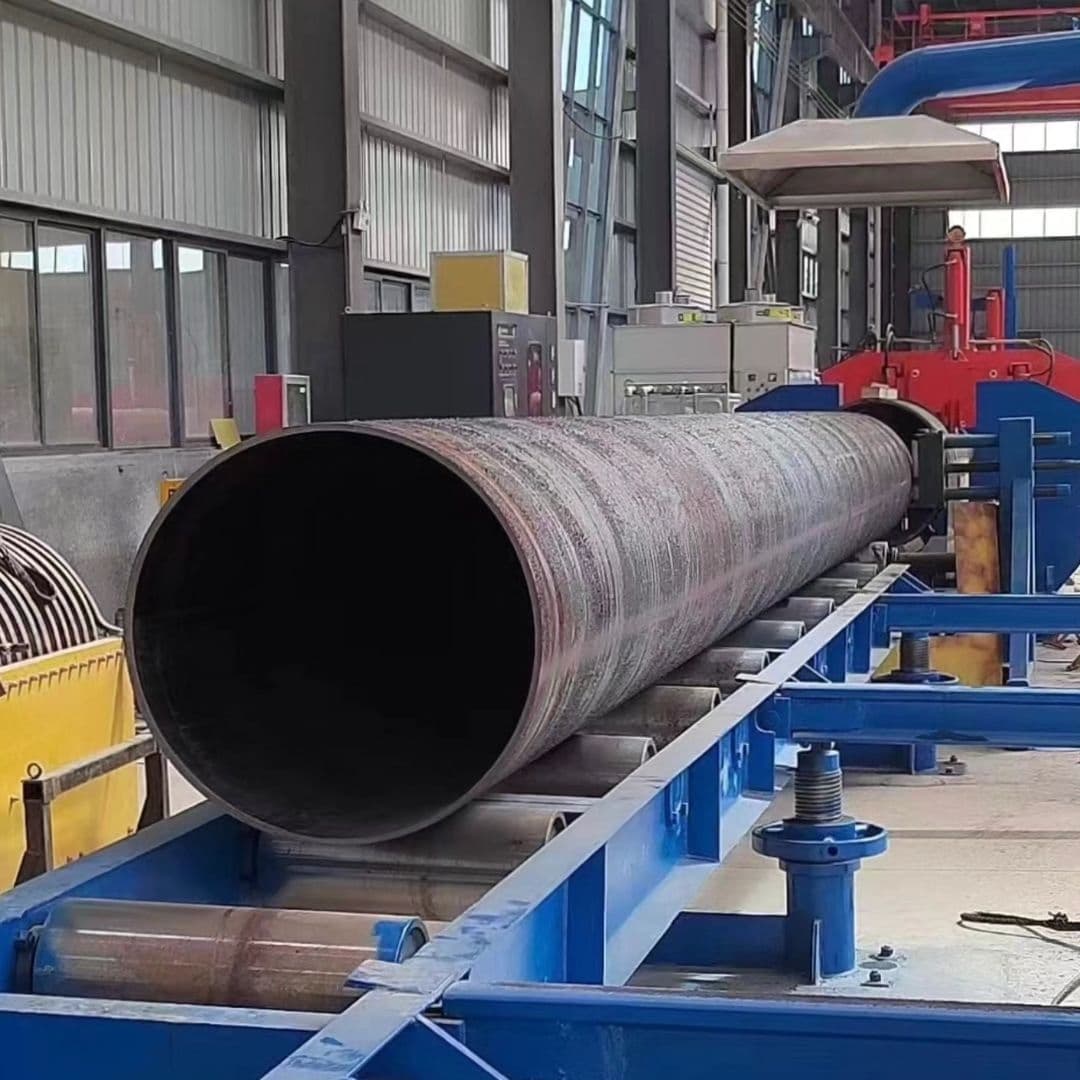 Tubería de Diámetros Mayores en un taller industrial, siendo procesada sobre una línea de producción, con maquinaria y equipos alrededor.