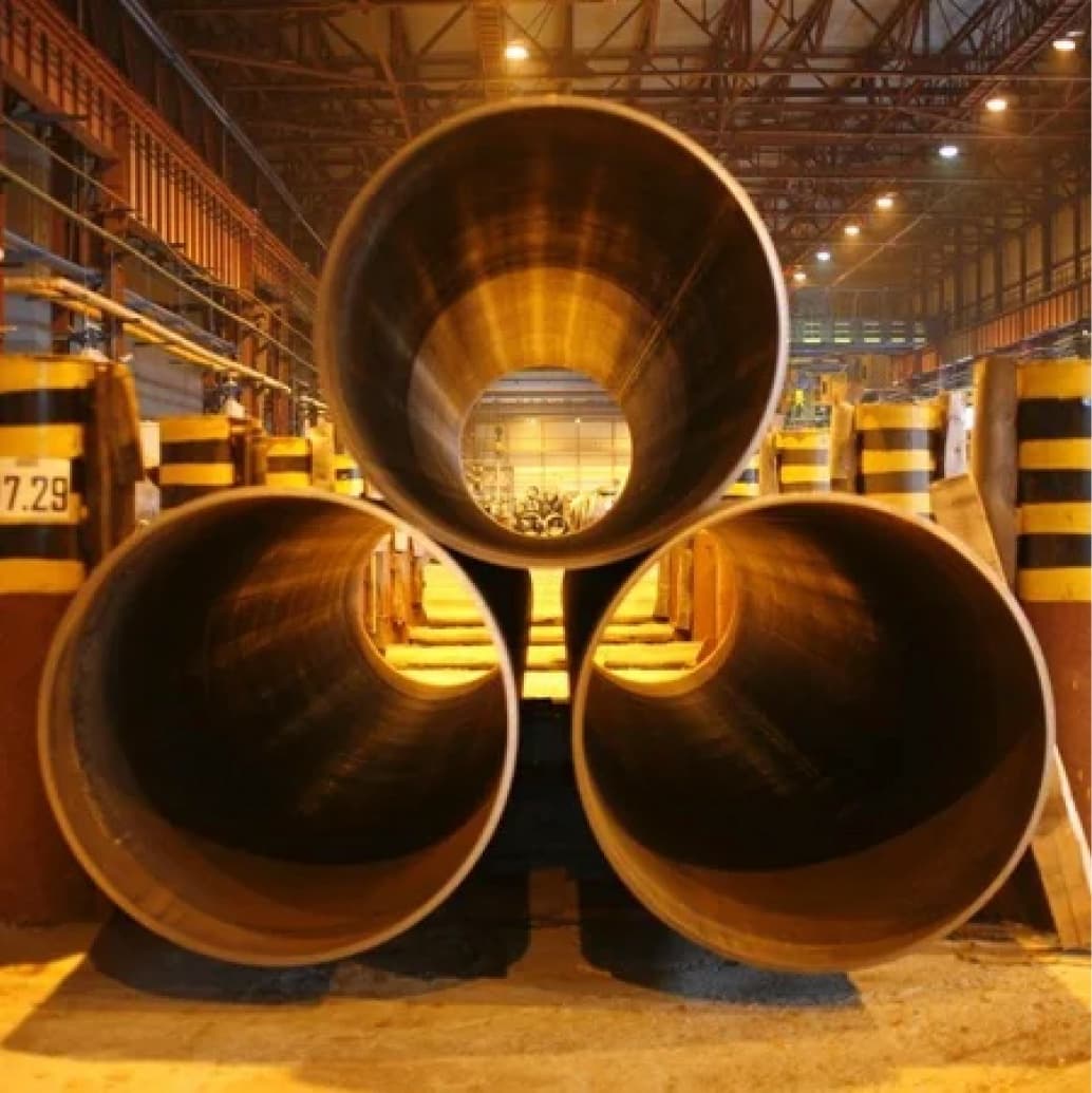 Tubería de Diámetros Mayores dispuestas en un entorno industrial, iluminadas con luces cálidas y rodeadas de elementos de construcción.
