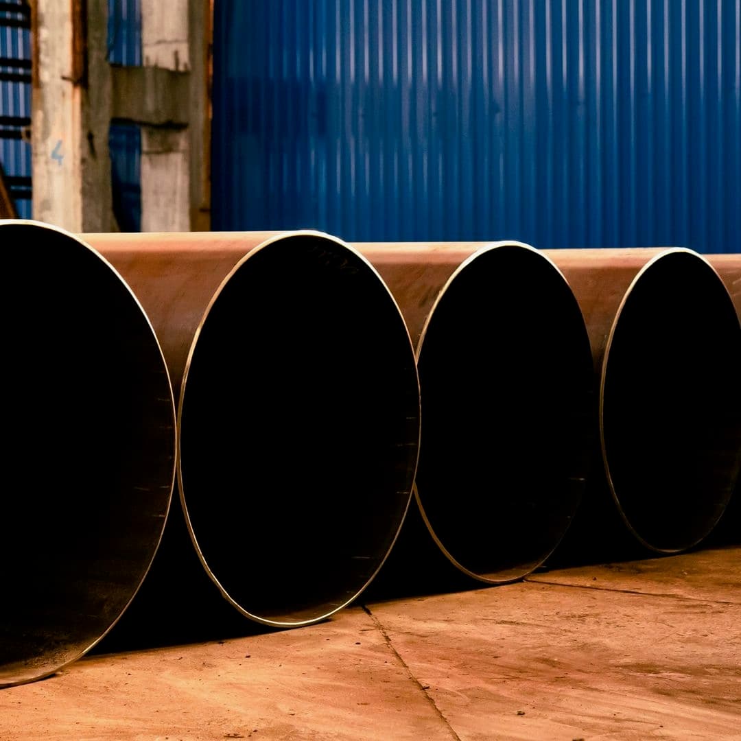 Tubería de Diámetros Mayores alineada en un espacio industrial, con fondo de pared azul y piso de cemento.