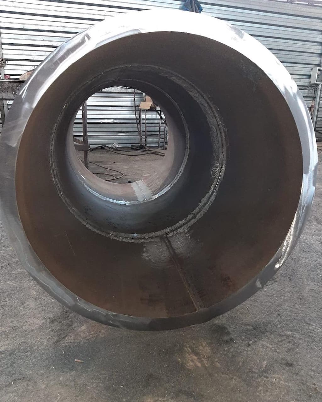 Tubería de Diámetros Mayores de acero con un acabado en su interior, mostrando la soldadura y el grosor del material, en un entorno industrial.