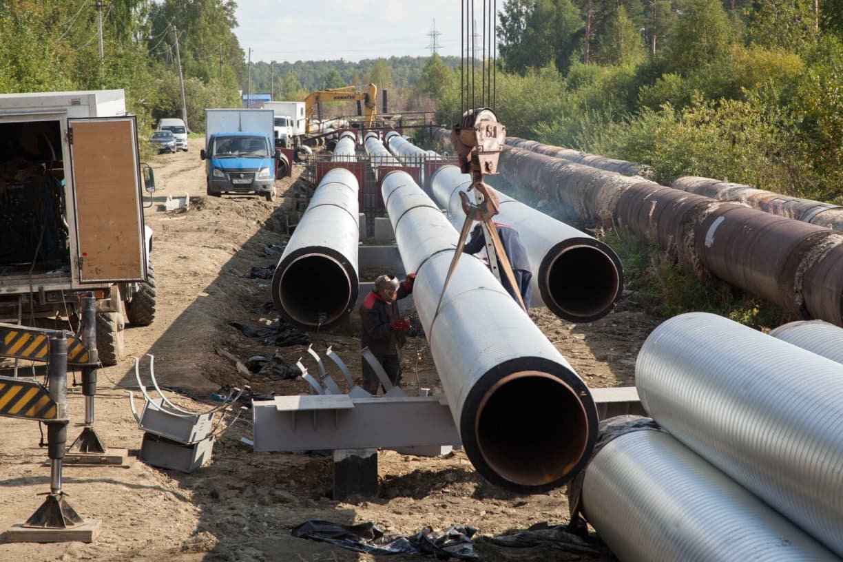 Se observan Tubería de Diámetros Mayores en un sitio de construcción, con trabajadores realizando actividades de instalación, grúas y vehículos de trabajo en un entorno natural con vegetación.