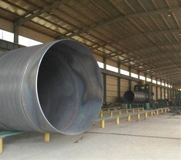 Almacén industrial con Tubería de Diámetros Mayores, donde se observan tubos grandes en proceso de fabricación, rodeados de maquinaria y un ambiente amplio y despejado.